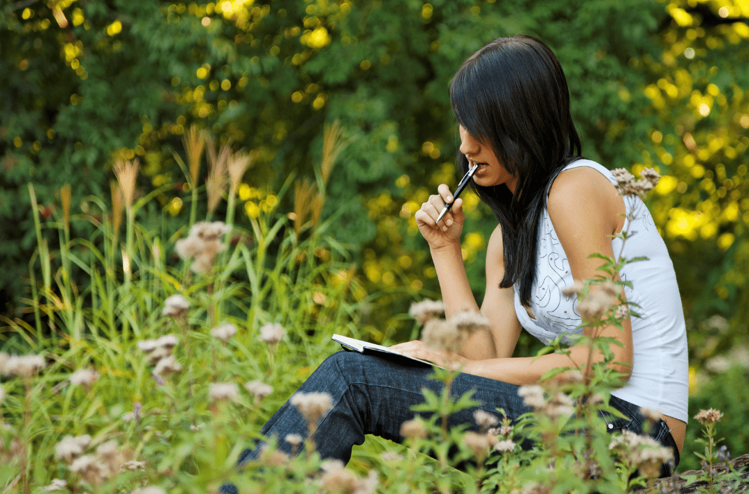 dayrise center picture 4 - Dayrise Wellness Young woman sitting in a field journaling, surrounded by tall grass and wildflowers
